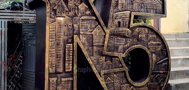 The N50 installation in daylight — bronze-finished cut metal, towers and buildings forming the numerals