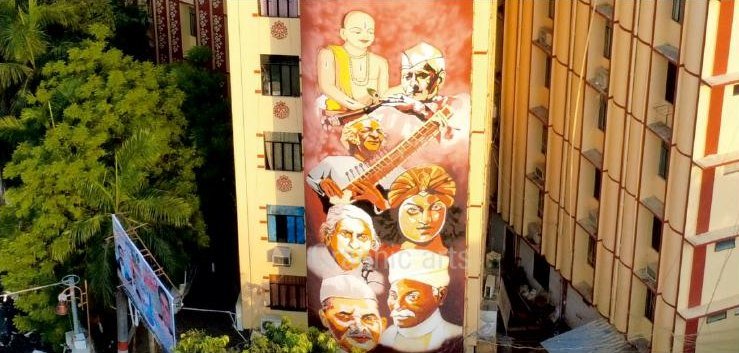 A multi-storey apartment facade painted full height with a composition of classical musicians and saints, executed by rope access